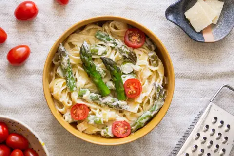Makaron tagliatelle ze szparagami i pomidorkami koktajlowymi w sosie śmietanowym.