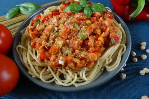 Talerz spaghetti z sosem z ciecierzycy, pomidorami, papryką i bazylią.