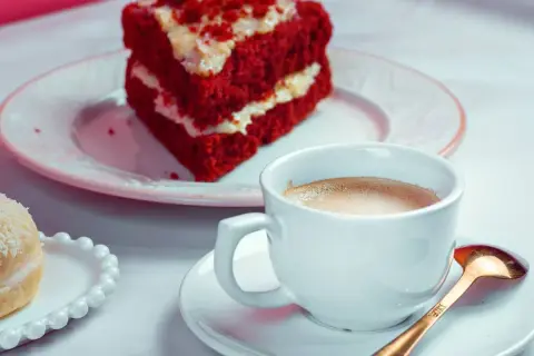 Kawa i kawałek ciasta Red Velvet na talerzyku.