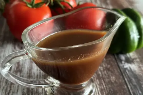 Sos balsamiczny w sosjerce, na tle pomidorów i papryki.