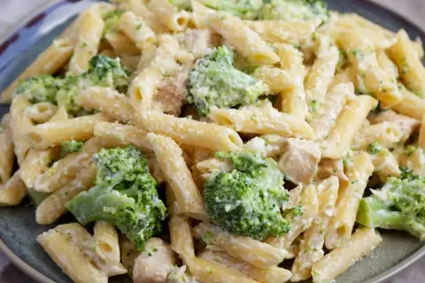 Makaron penne z brokułami i kurczakiem w kremowym sosie na talerzu.
