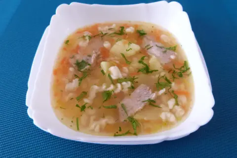 Pyszna zupa na żeberkach wieprzowych z ziemniakami, marchewką i makaronem, posypana natką pietruszki.