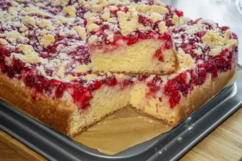 Puszyste ciasto drożdżowe z malinami i kruszonką, przekrojone na pół.