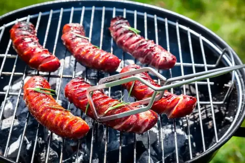 Kiełbaski grillowane na ruszcie, z gałązkami rozmarynu, w zbliżeniu.