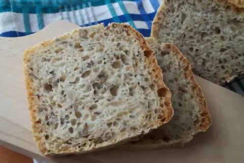 Kromki domowego chleba z ziarnami na desce do krojenia.