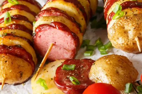 Kiełbasa i ziemniaki na patyku, zapiekane z sosem. Pyszny pomysł, co można zrobić z kiełbasy na obiad.