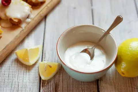 Miska z lukrem, cytryny i łyżeczka na drewnianym tle.