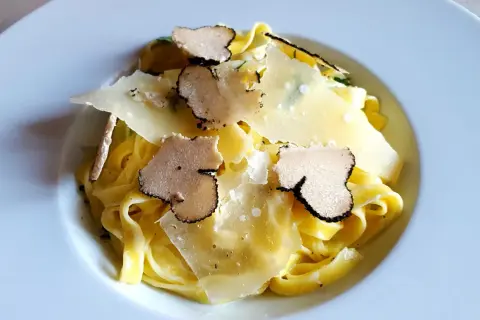 Tagliatelle z truflami ze słoika, posypane płatkami parmezanu. Luksusowy smak w każdym kęsie.