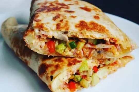 Złożona tortilla z jajkiem, serem, szynką i warzywami, usmażona na patelni.