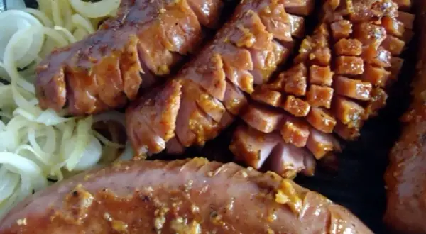 Pyszna kiełbasa grillowa z serem, pokrojona w plastry, podana na cebuli. Idealny przepis na letnie grillowanie!