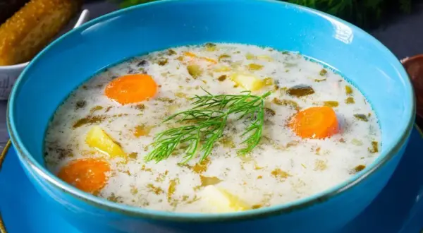 Aksamitna zupa ogórkowa z marchewką i ziemniakami, ozdobiona koperkiem. Idealna na obiad, gdy zastanawiasz się, co dodać do zupy ogórkowej.