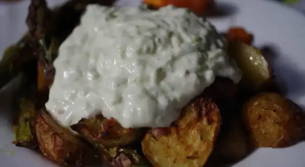 Gęsty sos tzatziki na pieczonych ziemniakach i warzywach.