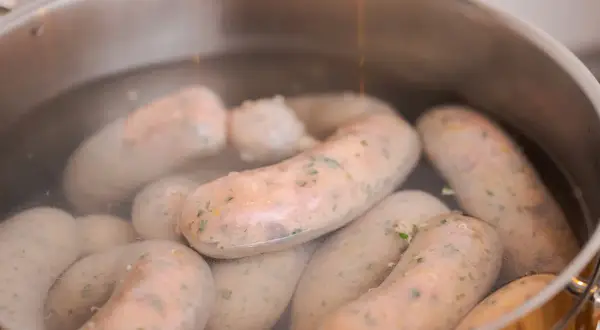 Biała kiełbasa gotuje się w garnku. Kluczowa jest odpowiednia temperatura parzenia, by była soczysta.