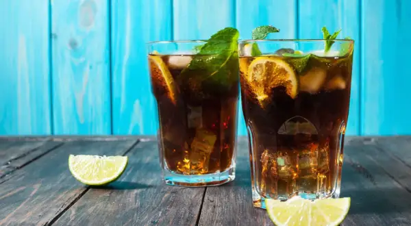 Dwa drinki z rumem, lodem, cytryną i miętą na drewnianym stole.