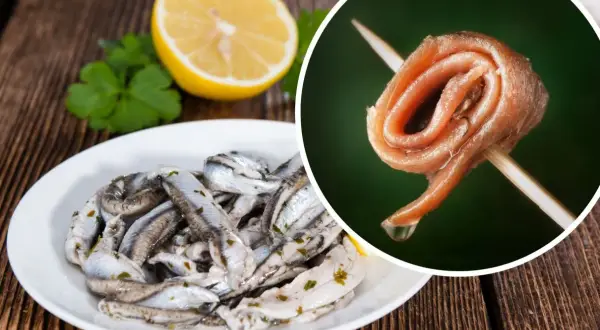 Anchois na talerzu i pojedynczy filet na wykałaczce, obok cytryna i natka.