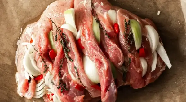 Surowa szynka z cebulą, papryczką chili i ziołami, gotowa do pieczenia na obiad.