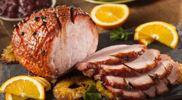 Pyszna, pieczona szynka wieprzowa z pomarańczą i ananasem, podana z żurawiną.
