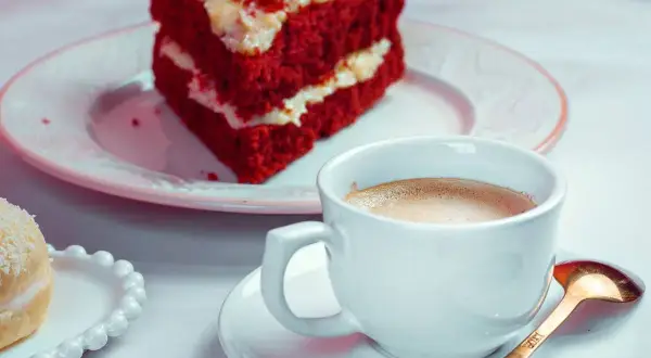 Kawa i kawałek ciasta Red Velvet na talerzyku.