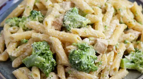 Makaron penne z brokułami i kurczakiem w kremowym sosie na talerzu.