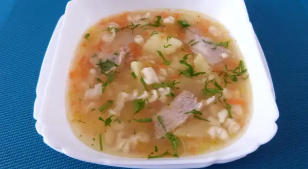 Pyszna zupa na żeberkach wieprzowych z ziemniakami, marchewką i makaronem, posypana natką pietruszki.