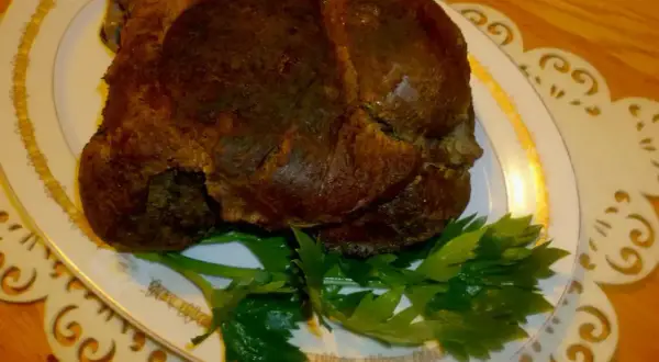 Upieczona dziczyzna na talerzu, ozdobiona natką pietruszki. Idealny przykład, jak upiec dziczyznę, by była soczysta i aromatyczna.