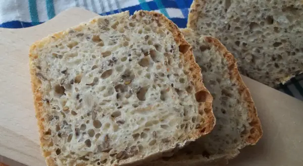 Kromki domowego chleba z ziarnami na desce do krojenia.