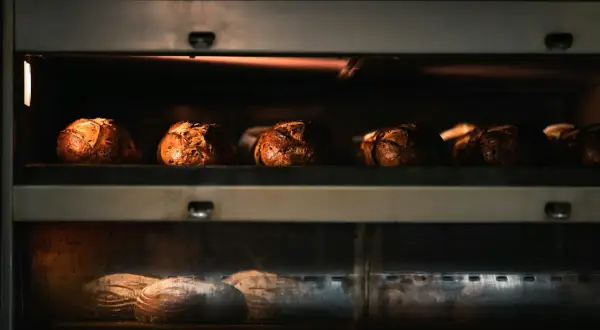 Kilka bochenków chleba piecze się w piekarniku, na dwóch poziomach.