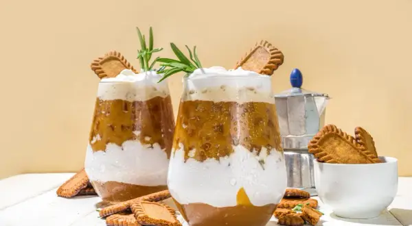 Dwa szklanki kawy z bitą śmietaną, ciasteczkami Biscoff i rozmarynem.