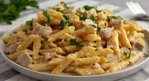 Penne w kremowym sosie ze smakowitymi kawałkami kurczaka, posypane świeżą natką pietruszki. Idealne danie na szybki obiad.
