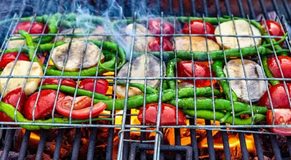 Warzywa na grillu: pomidory, papryczki i plastry bakłażana na ruszcie nad żarem.