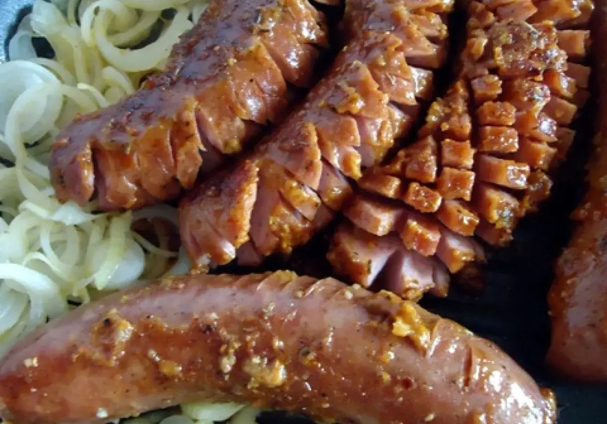 Pyszna kiełbasa grillowa z serem, pokrojona w plastry, podana na cebuli. Idealny przepis na letnie grillowanie!