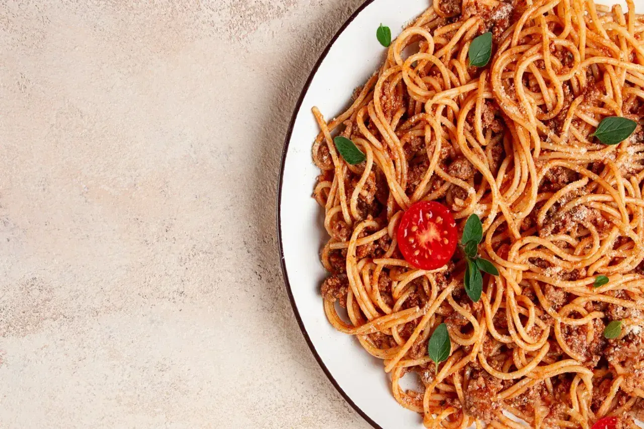 Talerz spaghetti bolognese z pomidorkiem i bazylią. Idealne dodatki do spaghetti, które zachwycą każdego smakosza.