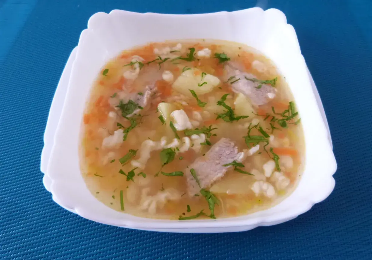 Pyszna zupa na żeberkach wieprzowych z ziemniakami, marchewką i makaronem, posypana natką pietruszki.
