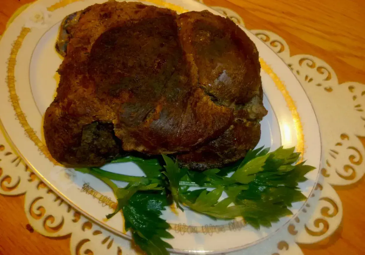 Upieczona dziczyzna na talerzu, ozdobiona natką pietruszki. Idealny przykład, jak upiec dziczyznę, by była soczysta i aromatyczna.