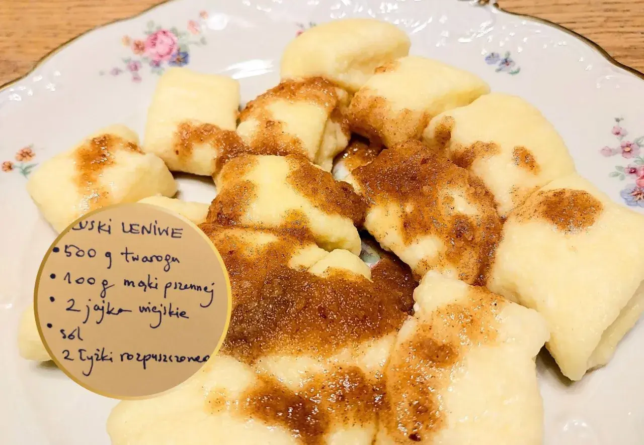 Kluski leniwe polane cynamonem na talerzu z przepisem.