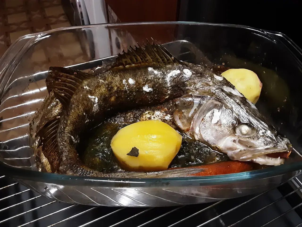 Pieczony sandacz z ziemniakami i marchewką w naczyniu żaroodpornym.