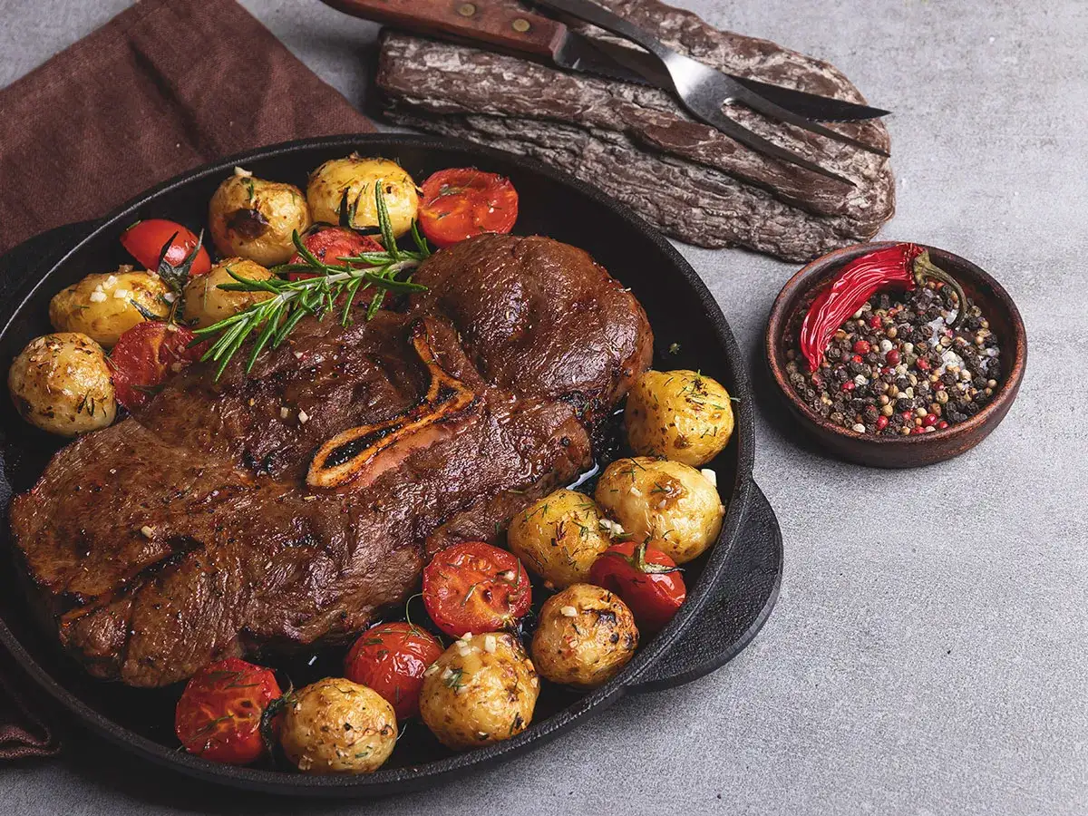 Soczysty stek z dziczyzny z pieczonymi ziemniakami i pomidorkami. Idealny przykład, jak przygotować dziczyznę do pieczenia, by była aromatyczna i krucha.