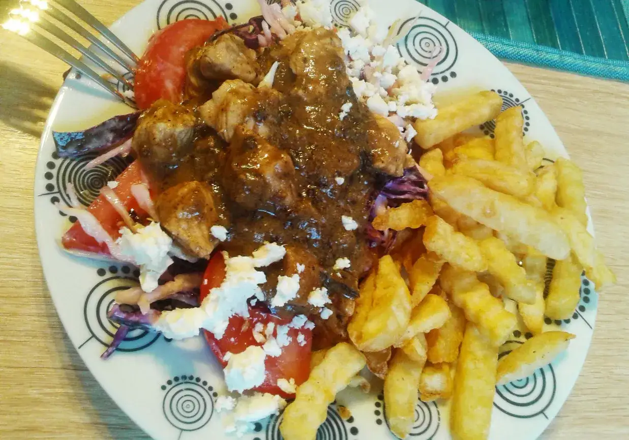 Talerz z kurczakiem w sosie, frytkami, pomidorami, fetą i surówką. Zastanawiasz się, ile kcal ma kebab z frytkami?