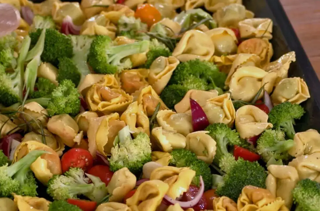 Szybkie dania z piekarnika: tortellini z brokułami, pomidorkami i czerwoną cebulą na blasze.
