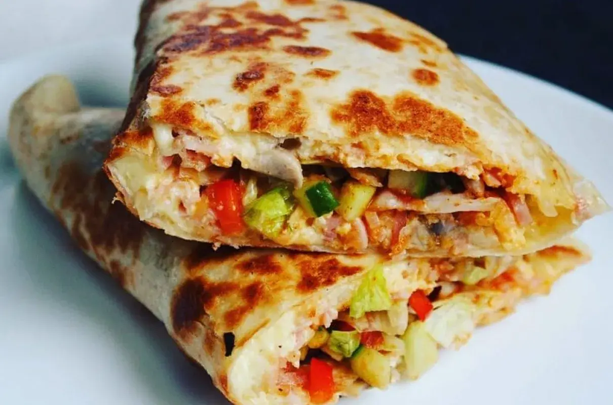 Złożona tortilla z jajkiem, serem, szynką i warzywami, usmażona na patelni.
