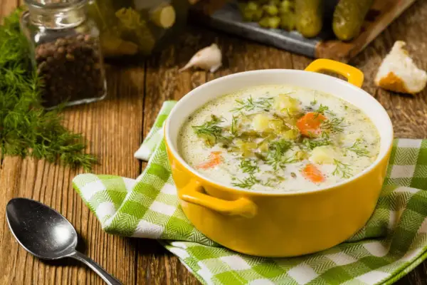 Aksamitna zupa ogórkowa z ziemniakami, ozdobiona świeżym koperkiem. Idealne zioła do zupy ogórkowej z ziemniakami to właśnie koperek i czosnek.
