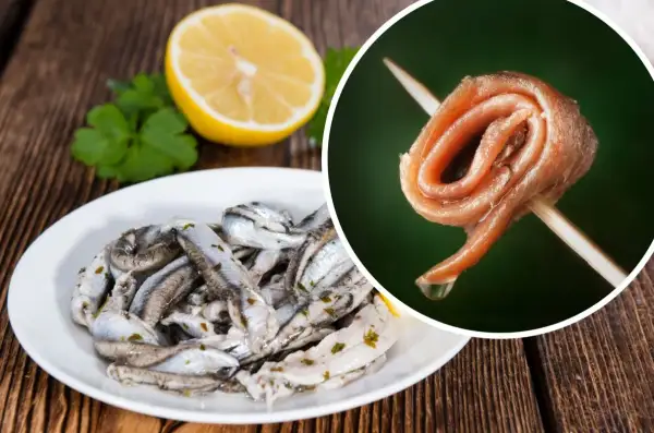 Anchois na talerzu i pojedynczy filet na wykałaczce, obok cytryna i natka.