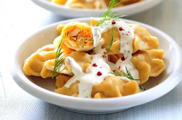 Pyszne pierogi z farszem, polane sosem śmietanowym i posypane koperkiem. Idealne, by zastanowić się, co zrobić na piątkowy obiad.