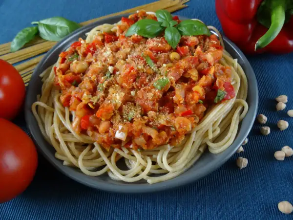 Talerz spaghetti z sosem z ciecierzycy, pomidorami, papryką i bazylią.