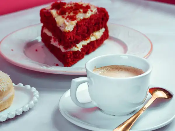 Kawa i kawałek ciasta Red Velvet na talerzyku.