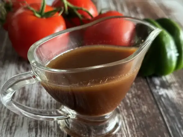 Sos balsamiczny w sosjerce, na tle pomidorów i papryki.