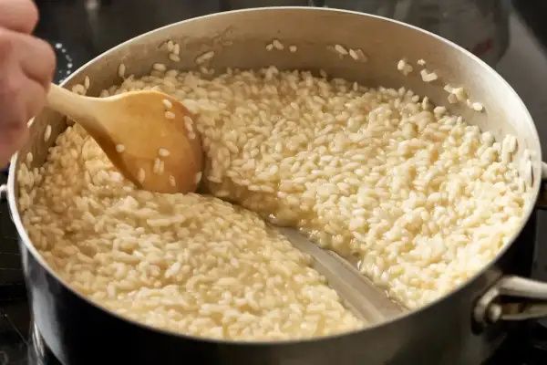 Gotowanie kremowego risotto w garnku, mieszane drewnianą łyżką.