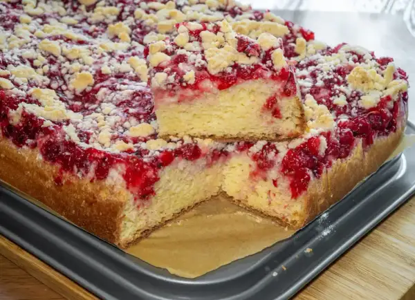 Puszyste ciasto drożdżowe z malinami i kruszonką, przekrojone na pół.