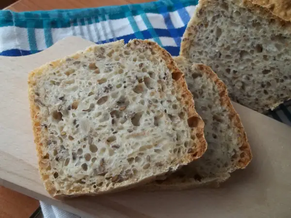 Kromki domowego chleba z ziarnami na desce do krojenia.