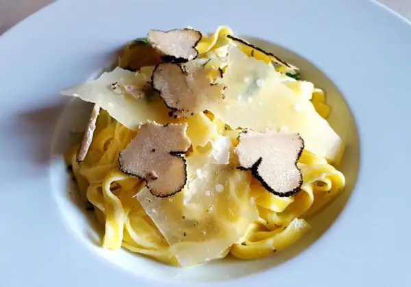 Tagliatelle z truflami ze słoika, posypane płatkami parmezanu. Luksusowy smak w każdym kęsie.
